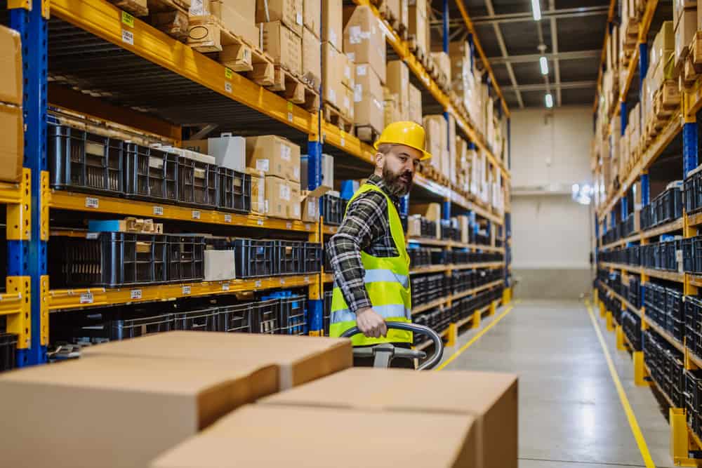 Male warehouse worker dragging a pallet truck